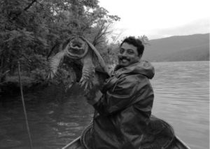 a man triumphantly holds a large turtle