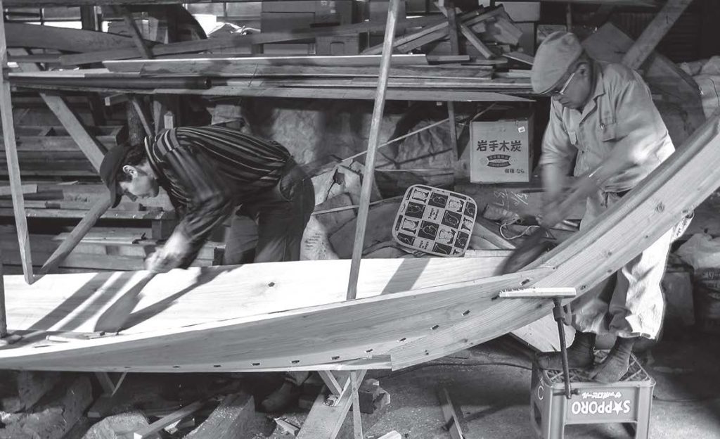 photo of two men building a wooden boat