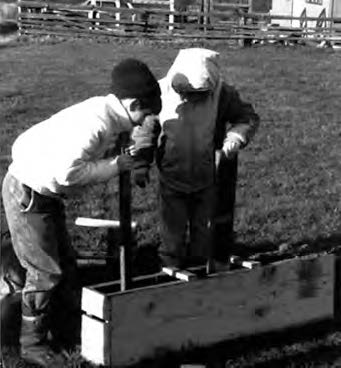 two children press dirt into a rectangular mold