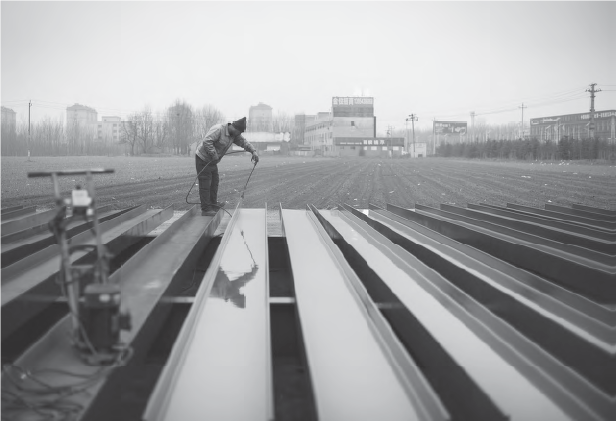 A worker spray-painting steel girders