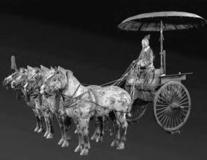 a bronze statue of a man riding a chariot led by four horses