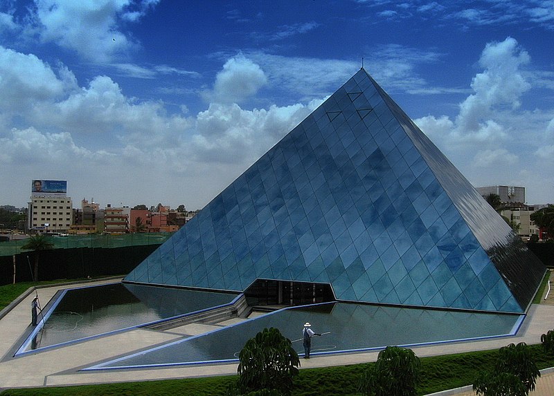 a glass pyramid that reflects the blue and cloudy sky above it