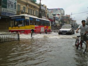 a photo of a bus and car submerged in flood water on a city street