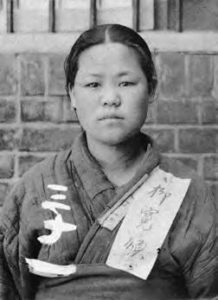 photograph of a woman in robes, with writing on them