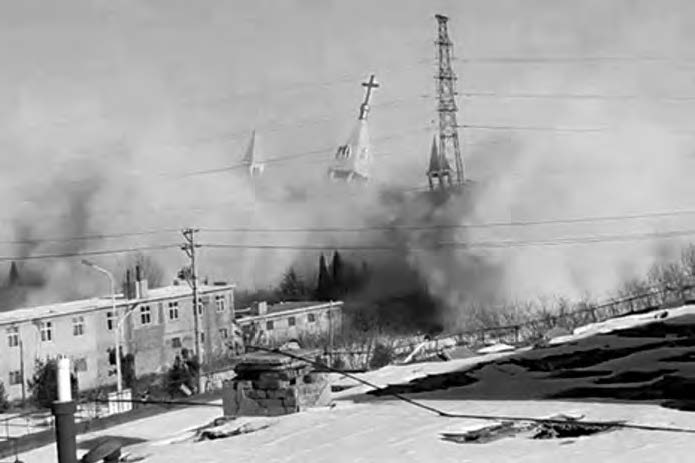 a photo of a church crumbling into dust. the top steeple can be seen falling