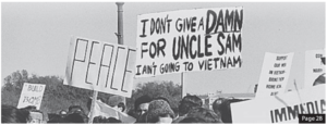 Image of people holding protest signs. They read "peace" and "I Don't give a damn for uncle sam I ain't going to Vietnam"