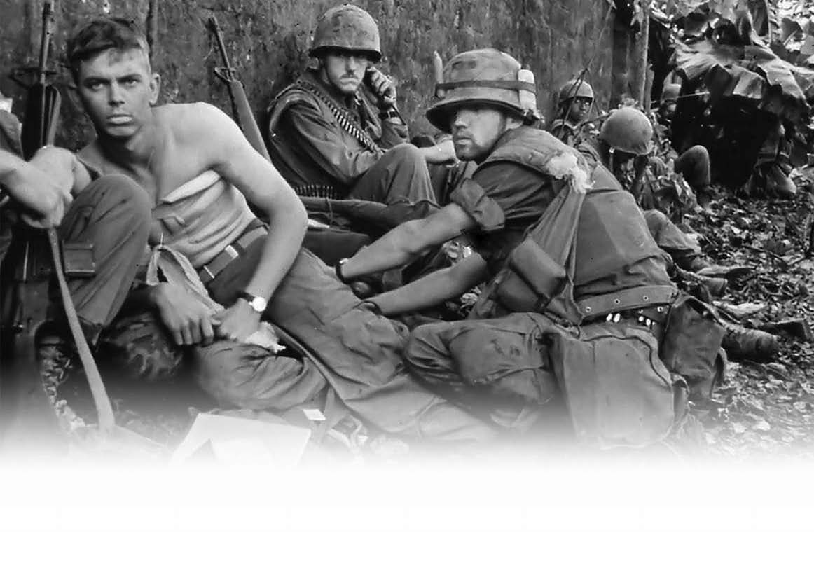 black and white photo of men in military uniforms, leaning against a wall