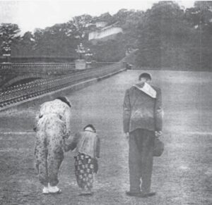 black and white photo of a man, woman, and child bowing