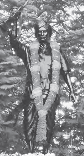 statue of a man holding a gan and wearing a garland of flowers around his neck