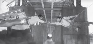 two men are jumping and reaching towards each other, one holding a flag as he does so