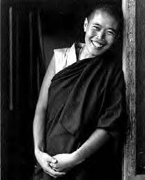 a bald person smiles. they are wearing robes