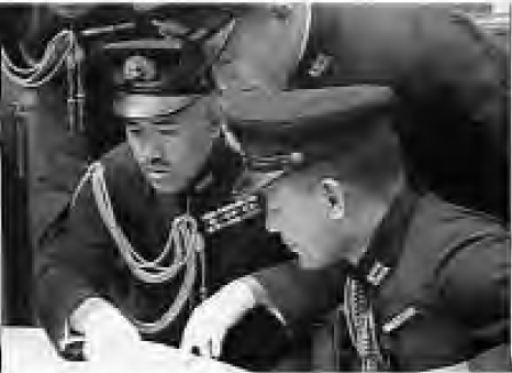 two men in military uniforms look at a paper
