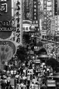 photo of a crowded street between large buildings and advertisements