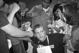 teens group around a boy, placing colored papers towards him