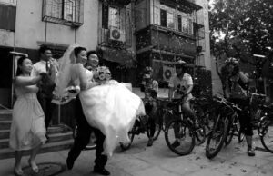 photograph of a man in a suit holding a woman in a white wedding dress