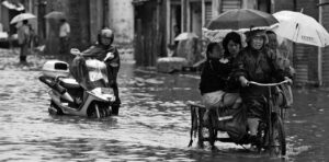 photo of a woman biking and a man walking his moped