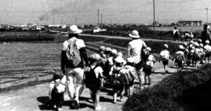 Students walk down a street, presumably they are on a field trip to study the environment. 